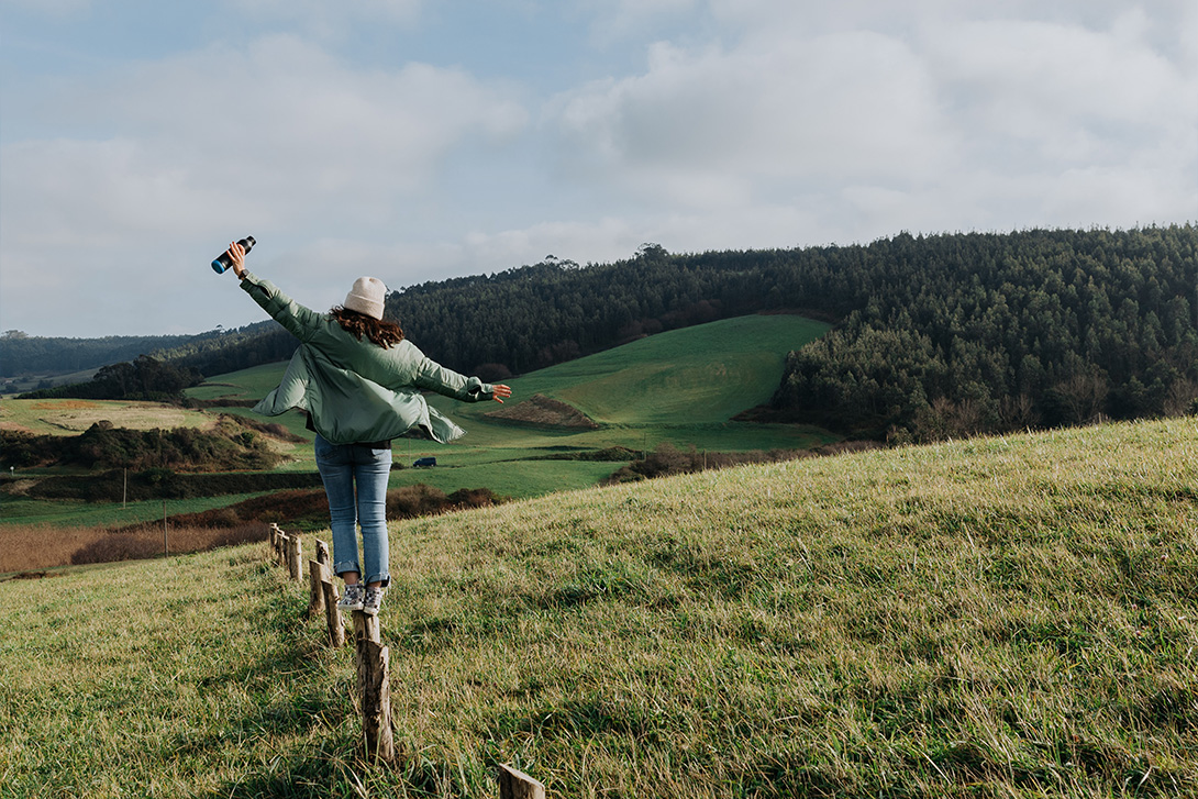 woman balancing on a fence post in the countryside