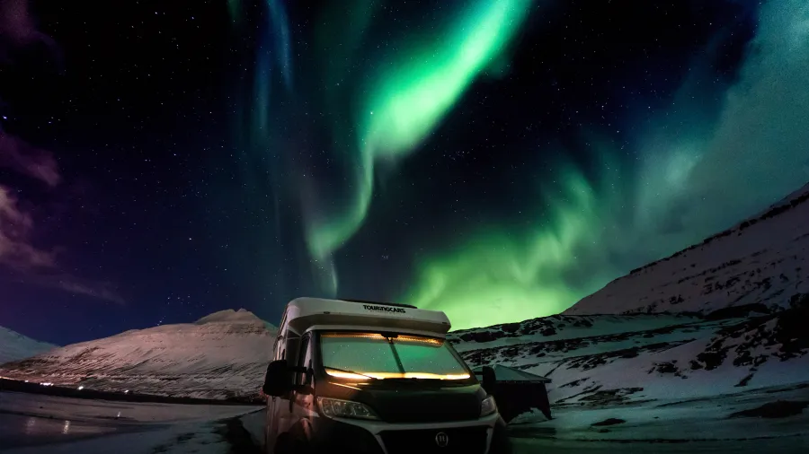 camper van under sky of aurora borealis
