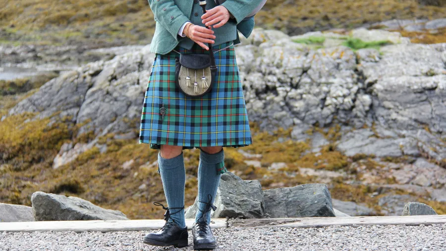 person in teal kilt playing bagpipes